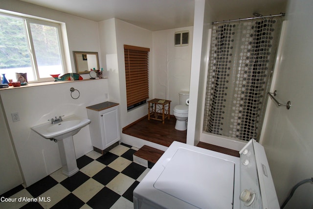 bathroom with toilet, washer / clothes dryer, and a shower with curtain