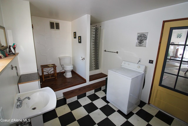 bathroom with sink, curtained shower, toilet, and washer / dryer