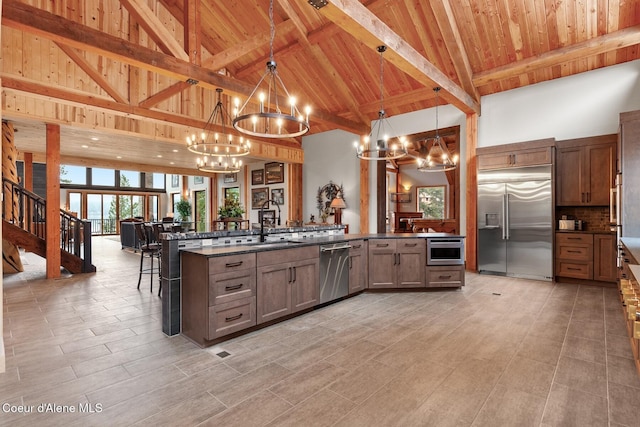 kitchen with pendant lighting, a notable chandelier, dark countertops, appliances with stainless steel finishes, and open floor plan