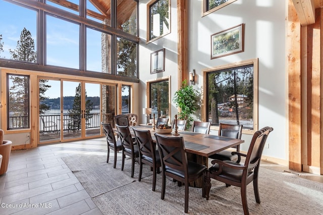 dining room featuring a high ceiling, a water view, visible vents, and wood tiled floor