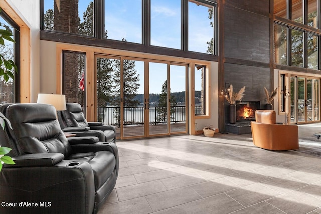 living area featuring french doors, a water view, a fireplace, and a towering ceiling