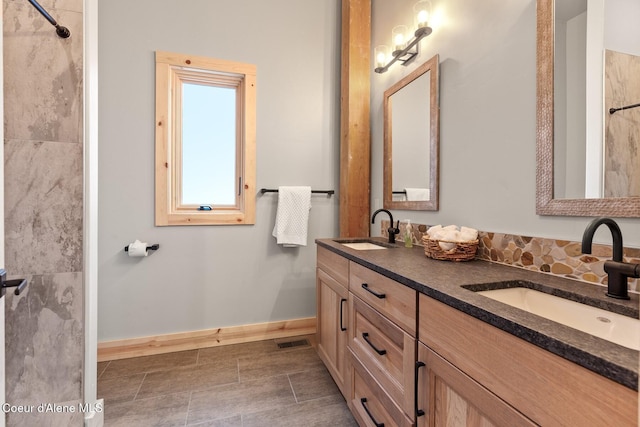 bathroom with double vanity, baseboards, visible vents, and a sink