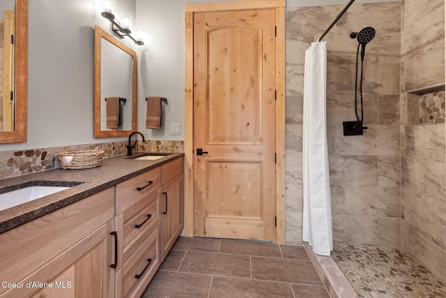 bathroom featuring double vanity, a sink, and tiled shower