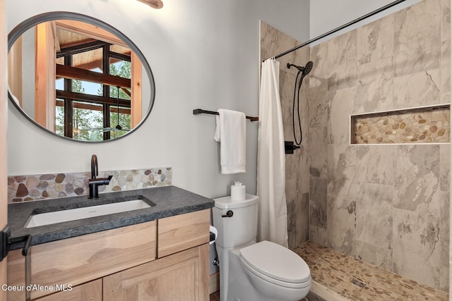 full bathroom featuring tiled shower, vanity, and toilet