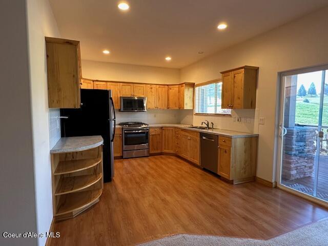 kitchen with sink, hardwood / wood-style floors, appliances with stainless steel finishes, and tasteful backsplash