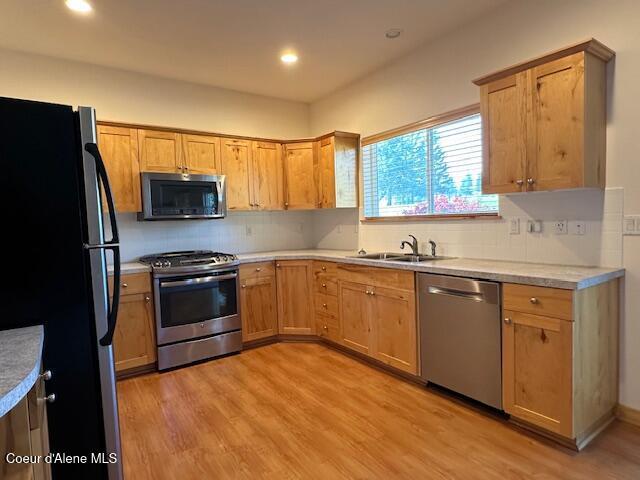 kitchen featuring sink, light hardwood / wood-style floors, decorative backsplash, and stainless steel appliances