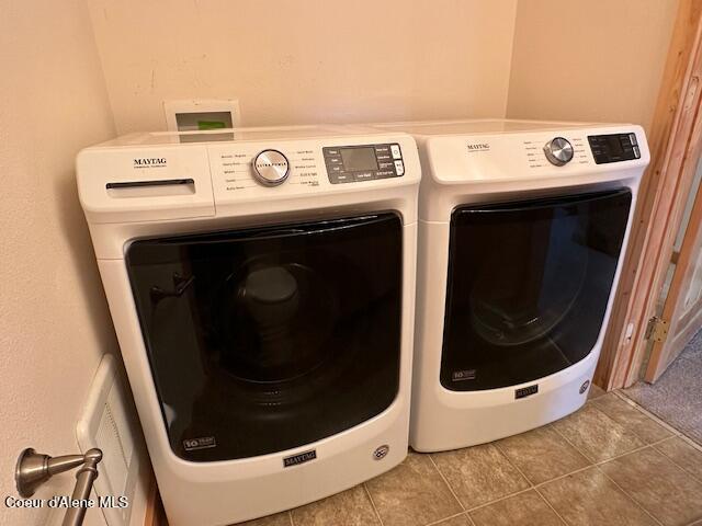 laundry area with independent washer and dryer and tile patterned floors