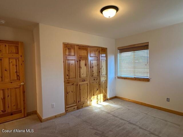 unfurnished bedroom featuring light colored carpet and a closet