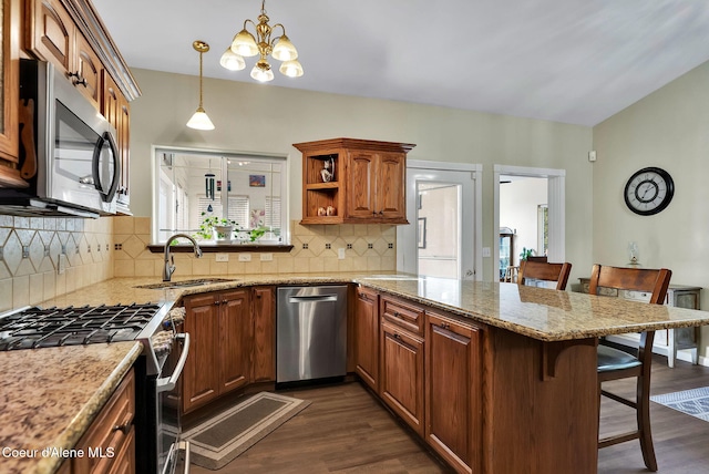 kitchen with a breakfast bar, sink, appliances with stainless steel finishes, kitchen peninsula, and pendant lighting