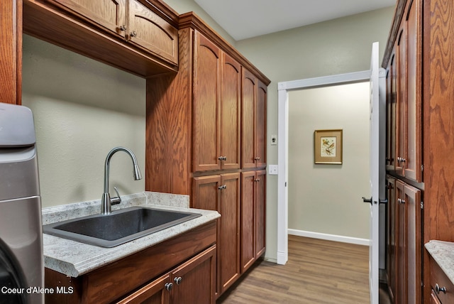 kitchen with light stone countertops, sink, and light wood-type flooring