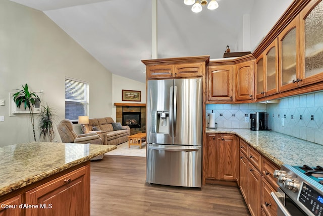 kitchen with stainless steel appliances, light stone countertops, dark hardwood / wood-style floors, and a fireplace