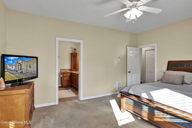 bedroom featuring ensuite bathroom, light colored carpet, and ceiling fan