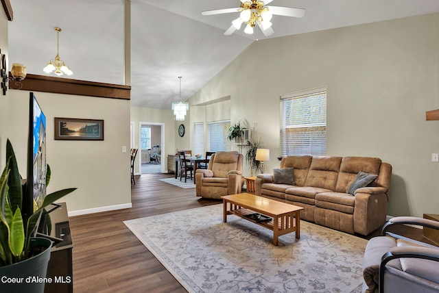 living room with dark wood-type flooring, a healthy amount of sunlight, ceiling fan with notable chandelier, and high vaulted ceiling