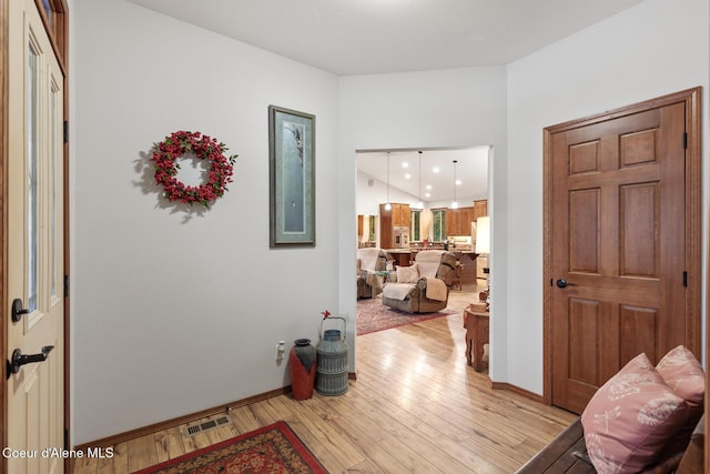hallway featuring light wood-style floors, baseboards, and visible vents