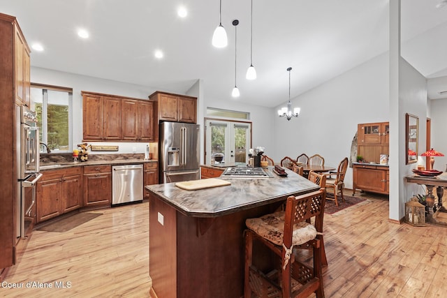 kitchen featuring dark countertops, appliances with stainless steel finishes, light wood finished floors, a breakfast bar area, and a center island