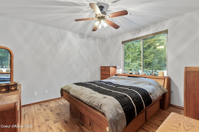 bedroom with light wood-type flooring, a ceiling fan, and baseboards