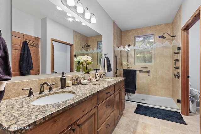 full bath featuring double vanity, a shower stall, a sink, and tile patterned flooring