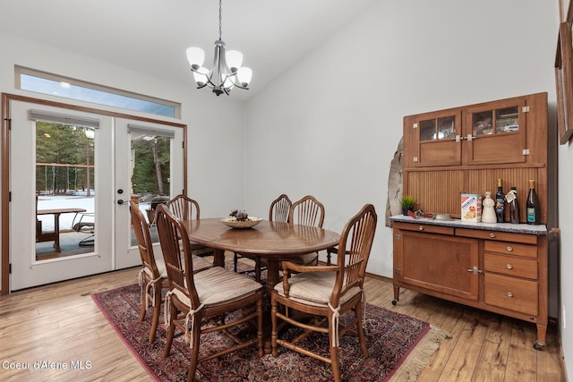 dining room featuring french doors, light wood-type flooring, high vaulted ceiling, and an inviting chandelier
