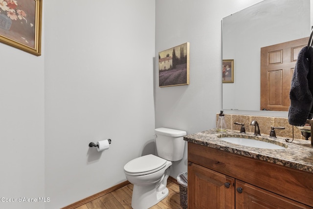 bathroom with toilet, baseboards, wood finished floors, and vanity