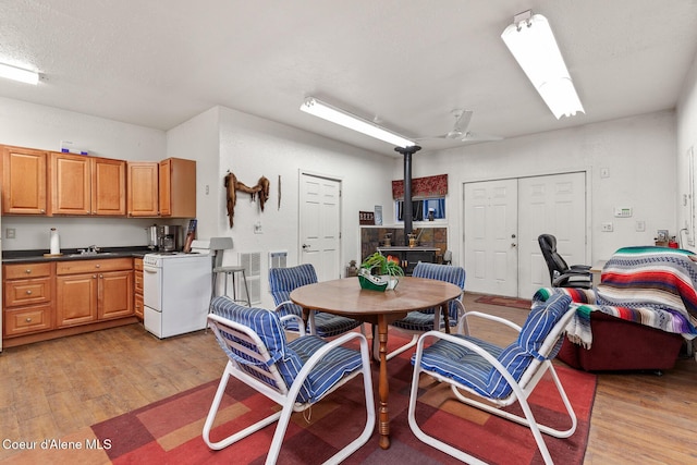 dining room featuring a wood stove, ceiling fan, and light wood finished floors