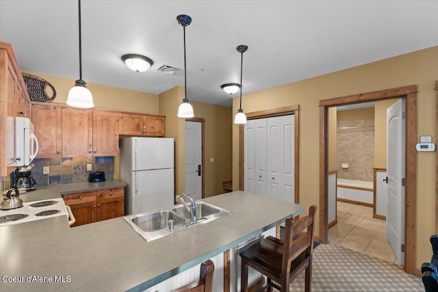 kitchen with pendant lighting, sink, white appliances, light tile patterned floors, and kitchen peninsula