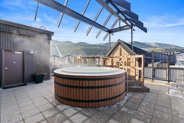 view of patio with a mountain view and a hot tub