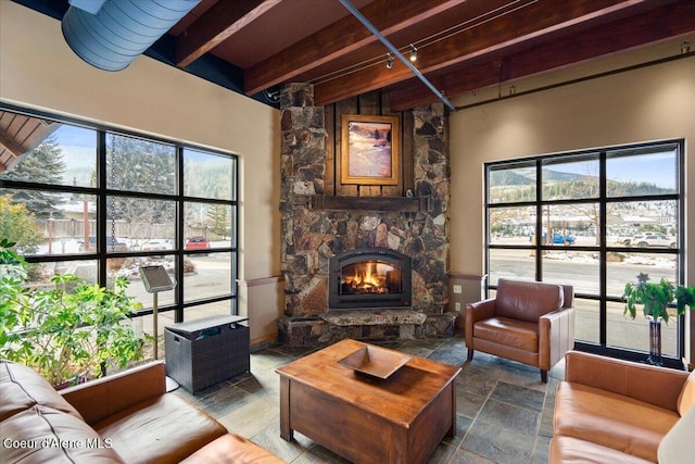 living room featuring a stone fireplace and beam ceiling