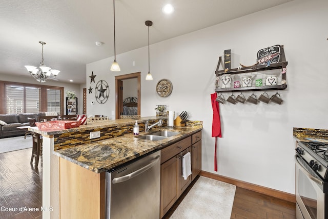 kitchen featuring sink, decorative light fixtures, light wood-type flooring, kitchen peninsula, and stainless steel appliances