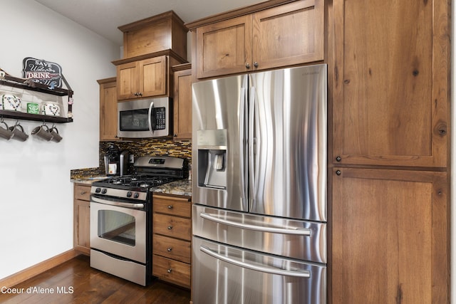 kitchen featuring dark wood-type flooring, stainless steel appliances, tasteful backsplash, and dark stone countertops