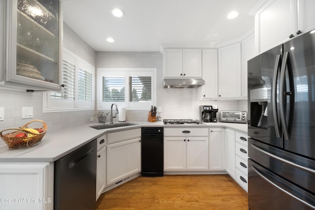 kitchen featuring sink, tasteful backsplash, appliances with stainless steel finishes, light hardwood / wood-style floors, and white cabinets