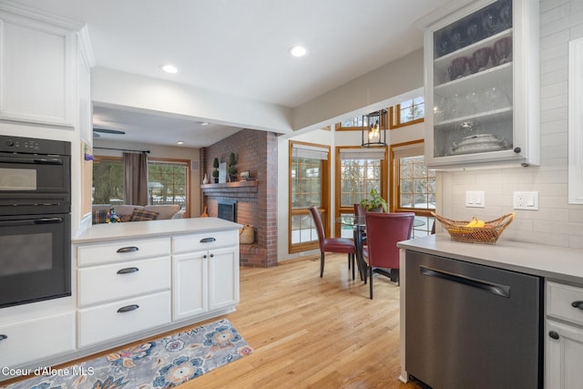 kitchen featuring white cabinetry, double oven, backsplash, and stainless steel dishwasher