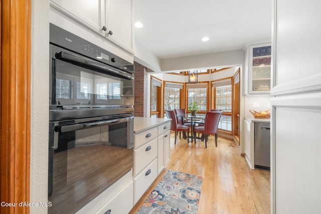 kitchen with white cabinetry, double oven, light hardwood / wood-style floors, and dishwasher