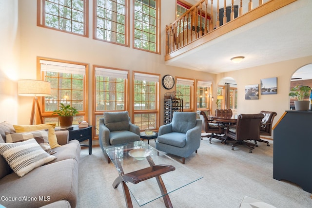 carpeted living room featuring a towering ceiling