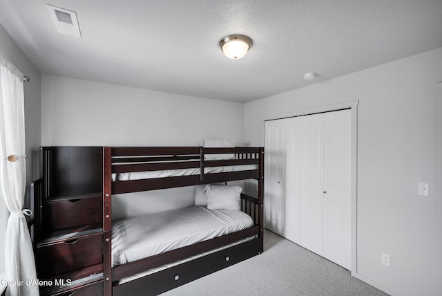 carpeted bedroom featuring a closet and a textured ceiling