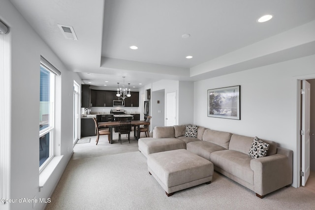 carpeted living room featuring an inviting chandelier and a tray ceiling