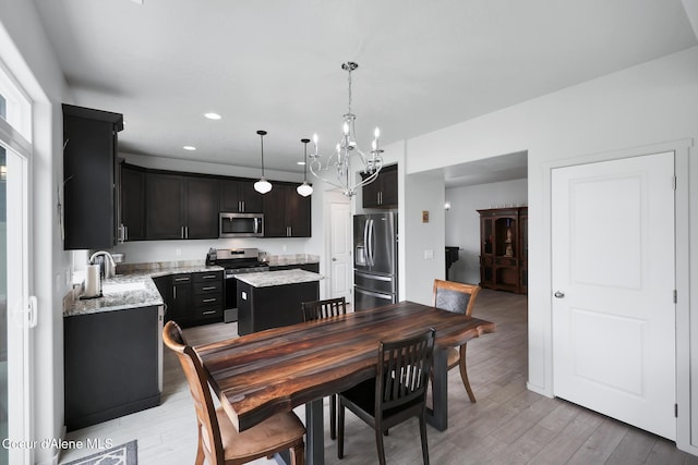 dining space with a notable chandelier, light hardwood / wood-style floors, and sink