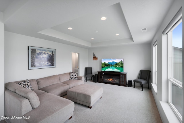 carpeted living room featuring a tray ceiling