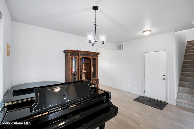 miscellaneous room featuring an inviting chandelier and light hardwood / wood-style floors