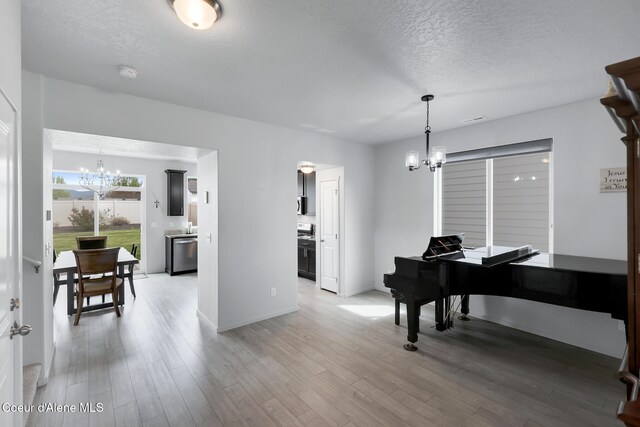 miscellaneous room featuring an inviting chandelier, a textured ceiling, and hardwood / wood-style flooring