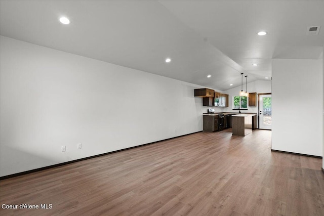 unfurnished living room featuring hardwood / wood-style flooring and vaulted ceiling