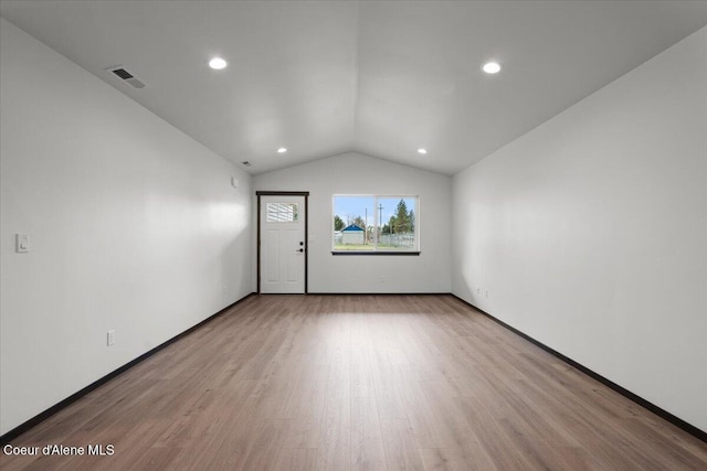 spare room with lofted ceiling and light wood-type flooring