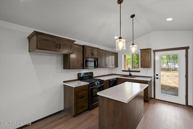 kitchen featuring lofted ceiling, sink, a kitchen island, gas range, and decorative light fixtures