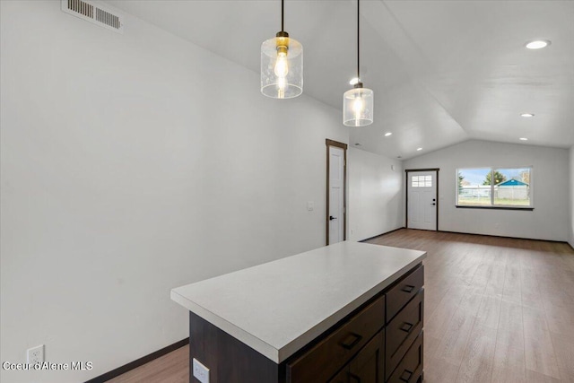 kitchen featuring lofted ceiling, hanging light fixtures, a center island, dark brown cabinets, and light wood-type flooring