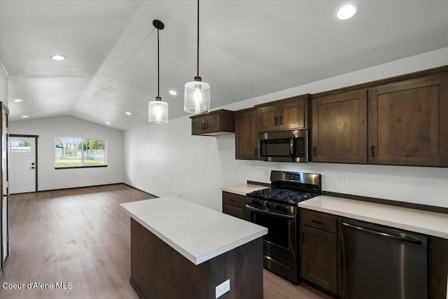 kitchen with appliances with stainless steel finishes, pendant lighting, lofted ceiling, a center island, and dark brown cabinets