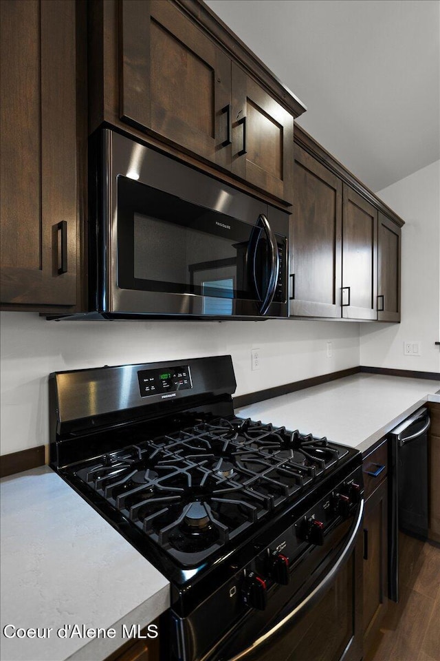 kitchen featuring dark wood-type flooring, dark brown cabinetry, and gas range oven