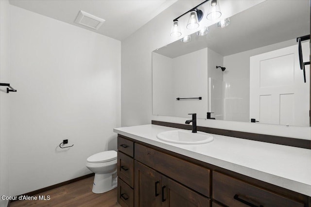 bathroom featuring vanity, hardwood / wood-style flooring, toilet, and walk in shower