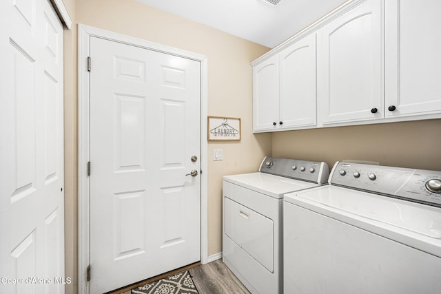 washroom with cabinets, hardwood / wood-style flooring, and washing machine and clothes dryer