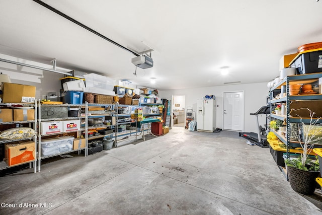 garage featuring a garage door opener and white fridge with ice dispenser