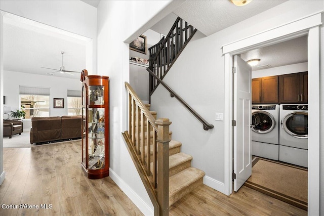 staircase featuring ceiling fan, hardwood / wood-style floors, a textured ceiling, and washer and clothes dryer