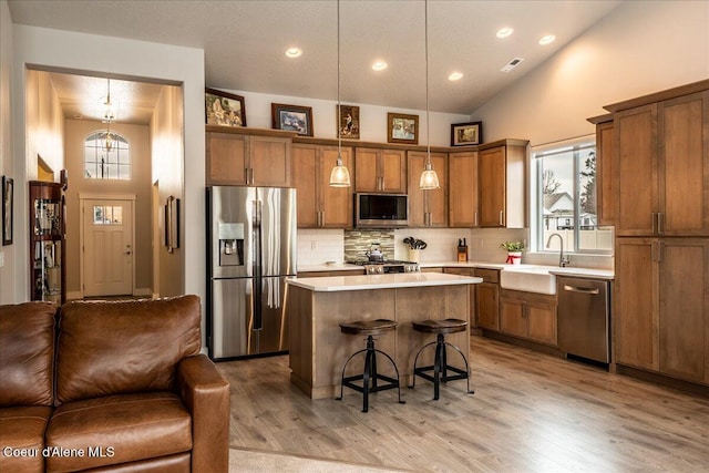 kitchen with pendant lighting, sink, a breakfast bar, appliances with stainless steel finishes, and a kitchen island